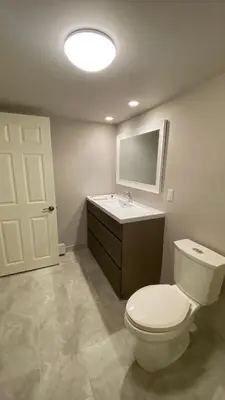 a bathroom with a toilet and a sink and a mirror at Cozy Basement in Richmond Hill