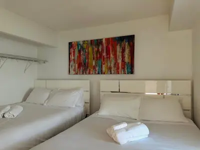 two beds in a room with a painting on the wall at LakeView 2Bdrms 2Baths with 3 real beds and parking in Toronto