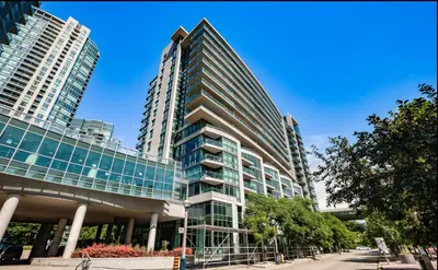 a tall building with glass windows on a street at Luxury Downtown Condo with CN tower views, Pool Access, Gym,Free Parking upon request at booking, accommodates 4 in Toronto
