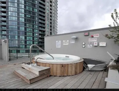 a hot tub sitting on top of a deck at Luxury Downtown Condo with CN tower views, Pool Access, Gym,Free Parking upon request at booking, accommodates 4 in Toronto