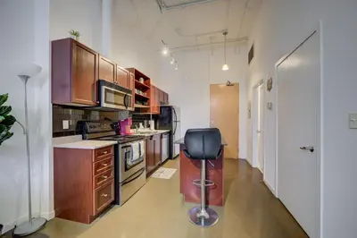 a kitchen with wooden cabinets and a black chair in it at Entire 1 bedroom in the heart of KW downtown across Google in Kitchener