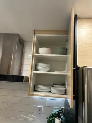 a cupboard with plates and dishes in a kitchen at Luxurious modern basement apartment in Pickering