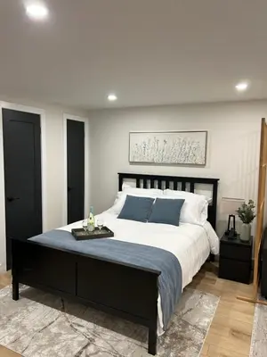 a bedroom with a large bed with blue pillows at Luxurious modern basement apartment in Pickering