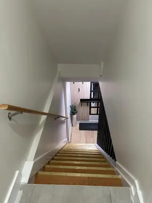 a staircase with white walls and wooden stairs at Luxurious modern basement apartment in Pickering