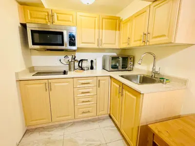 a kitchen with wooden cabinets and a sink and a microwave at Modern 1-Bedroom Apartment - Near Airport & Toronto Downtown in Brampton
