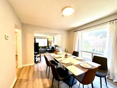 a dining room table with chairs and a large window at Cozy and spacious vacation home in Toronto in Toronto