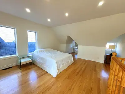 a bedroom with a white bed and a wooden floor at Deluxe Queen Rooms Downtown in Toronto