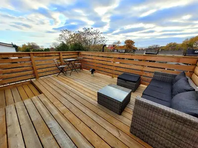 a deck with a couch and chairs and a table at Deluxe Queen Rooms Downtown in Toronto