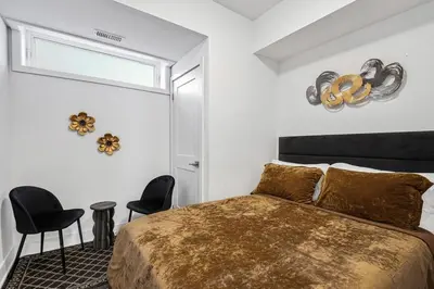 a bedroom with a bed and two chairs and a window at Cozy 2BR Family Friendly Retreat With Parking and Just 6 Minutes away from Niagara Falls in Niagara Falls