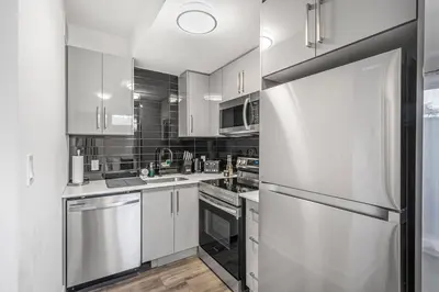 a kitchen with white cabinets and a stainless steel refrigerator at Cozy 2BR Family Friendly Retreat With Parking and Just 6 Minutes away from Niagara Falls in Niagara Falls