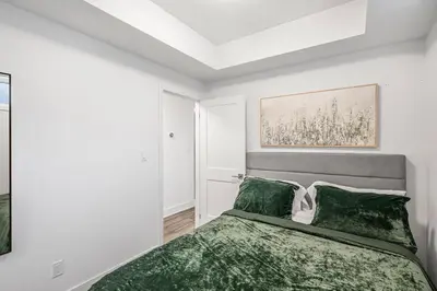 a bedroom with a bed with a green blanket at Cozy 2BR Family Friendly Retreat With Parking and Just 6 Minutes away from Niagara Falls in Niagara Falls