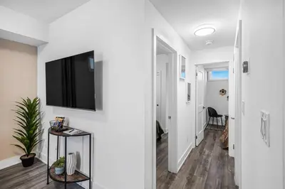 a hallway with a flat screen tv on a wall at Cozy 2BR Family Friendly Retreat With Parking and Just 6 Minutes away from Niagara Falls in Niagara Falls