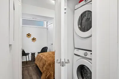 a bedroom with a washer and dryer next to a bed at Cozy 2BR Family Friendly Retreat With Parking and Just 6 Minutes away from Niagara Falls in Niagara Falls