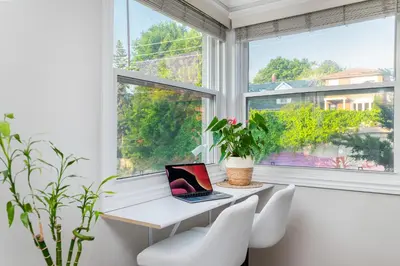 a laptop computer sitting on a white desk in a room with windows at Resort-like 4BR 3BA near Downtown, Four seasons Hot Tub, Gym, King Bed in Toronto