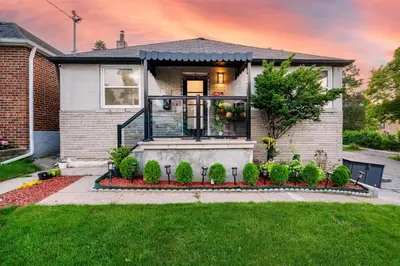 a house with a front porch with a lawn at Resort-like 4BR 3BA near Downtown, Four seasons Hot Tub, Gym, King Bed in Toronto
