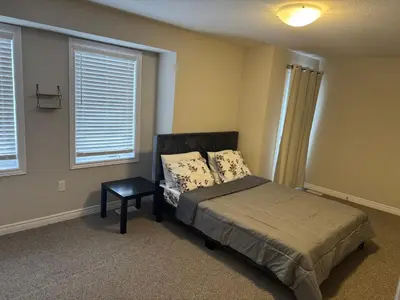 a bedroom with a bed and a table and two windows at A Compact family home in Milton in Milton