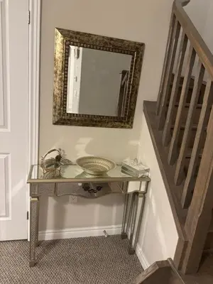 a mirror on a wall above a console table next to a staircase at A Compact family home in Milton in Milton