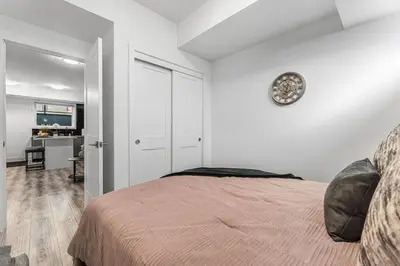a bedroom with a bed with a clock on the wall at NEW Stylish 1BR Apartment With BBQ and Situated Close to the Falls and Can Sleep 4 Guests in Niagara Falls