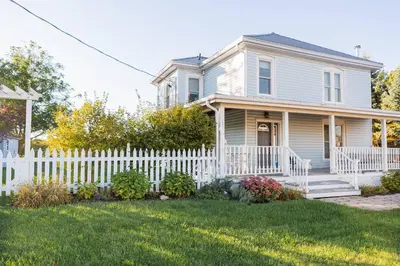 a white picket fence in front of a house at The Vue - Nestled by Roblin's Lake with a Hot Tub in Mountain View