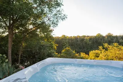 a jacuzzi tub in a yard with trees at The Vue - Nestled by Roblin's Lake with a Hot Tub in Mountain View
