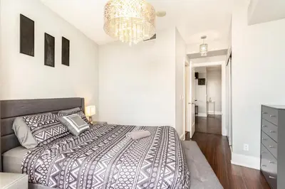 a bedroom with a large bed and a chandelier at Executive 2BR 2BATH Condo with Lakeview Steps from SQ1 in Mississauga