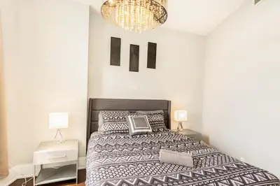 a bedroom with a large bed and a chandelier at Executive 2BR 2BATH Condo with Lakeview Steps from SQ1 in Mississauga