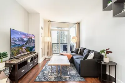 a living room with a couch and a tv at Executive 2BR 2BATH Condo with Lakeview Steps from SQ1 in Mississauga