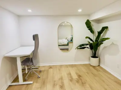 a desk and a chair in a room with a mirror at Family-Friendly 2BR Ground-Level Suite with Full Kitchen, Parking and 20 Minutes to Downtown in Toronto