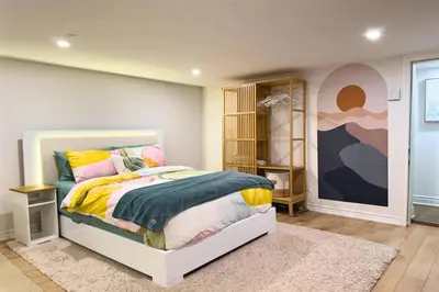 a bedroom with a bed and a painting on the wall at Family-Friendly 2BR Ground-Level Suite with Full Kitchen, Parking and 20 Minutes to Downtown in Toronto