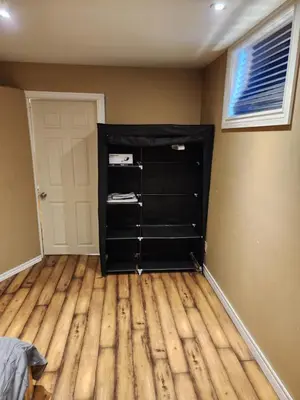a room with a black book shelf next to a door at The Cozy Den in Ingersoll