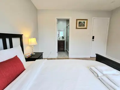 a bedroom with a large white bed with a red blanket at A Home Away-Cozy Guest Room in Toronto in Toronto