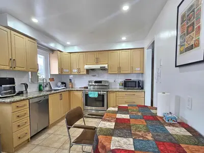 a kitchen with wooden cabinets and a table and chairs at A Home Away-Cozy Guest Room in Toronto in Toronto