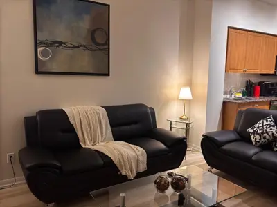 a living room with a black couch and a table at A lovely one bed room with Sunset Views in Toronto