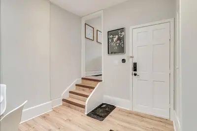 a white hallway with a white door and stairs at Casa Queen - Unique 2BR Suite in Leslieville in Toronto