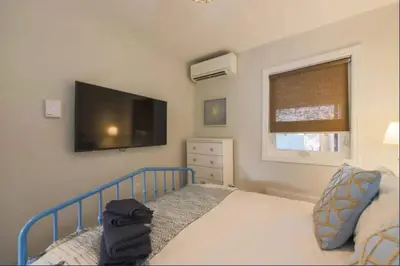 a bedroom with a bed and a flat screen tv at Casa Queen East - Modern 2BR Suite in Leslieville in Toronto
