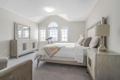 a white bedroom with a large bed and two windows at The Bliss in Bowmanville