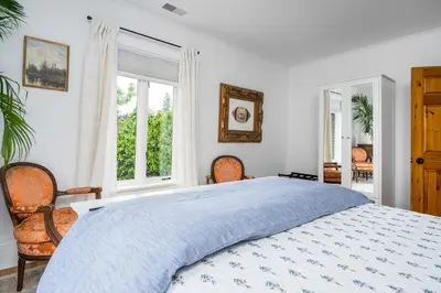 a bedroom with a bed and two chairs and windows at 3bed 2bath heritage duplex - Prime Location in Collingwood