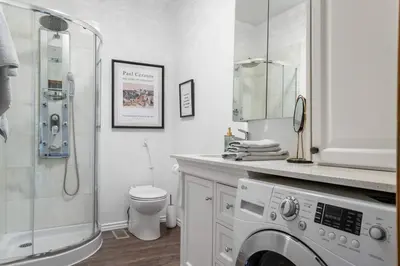 a white bathroom with a shower and a washing machine at 1 bedroom Garden Suite with parking, Best Location in Collingwood
