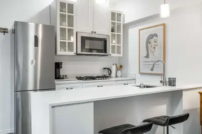 a kitchen with white cabinets and a stainless steel refrigerator at 1 bedroom Garden Suite with parking, Best Location in Collingwood