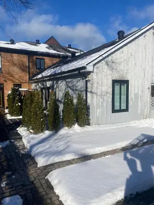 a house with snow on the ground next to a building at 1 bedroom Garden Suite with parking, Best Location in Collingwood