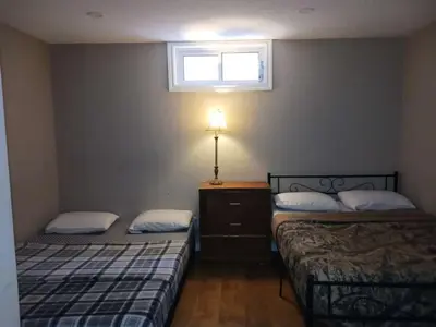 two beds in a small room with a window at CheapSleep Room Near Kitchener Airport- 24X7 Checkin in Kitchener
