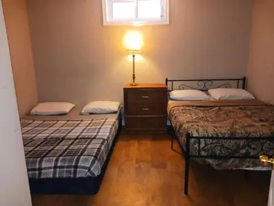 a room with two beds and a dresser and a window at CheapSleep Room Near Kitchener Airport- 24X7 Checkin in Kitchener