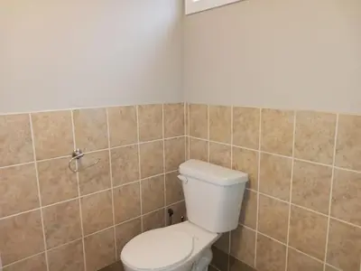 a bathroom with a toilet and a tiled wall at CheapSleep Room Near Kitchener Airport- 24X7 Checkin in Kitchener