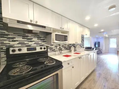 a kitchen with white cabinets and a black stove top oven at Cozy Walkout Suite in Vaughan
