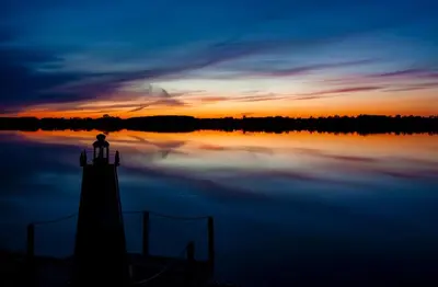 a person standing on a lighthouse on a lake at sunset at The Sweetgrass - 57 Butternut in Cherry Valley