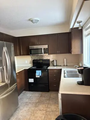 a kitchen with wooden cabinets and a black refrigerator at 2 beds suit in Kitchener