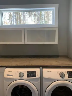 a laundry room with two washing machines and a window at McCracken's Mid Century Modern Luxury Cottage in Burleigh Falls