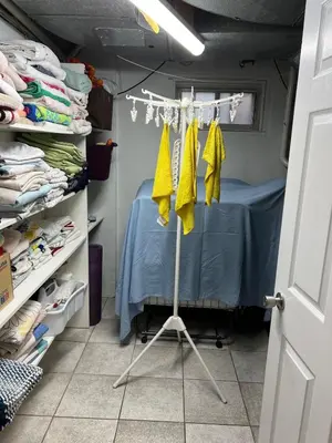 a room with a bed with yellow shirts on a clothes rack at Entire Basement Apartment in Toronto