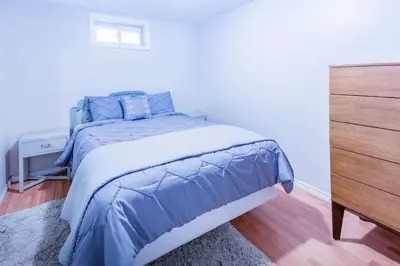 a bedroom with a bed with blue sheets and a dresser at Relax at The Mountaintop Chalet in Blue Mountains