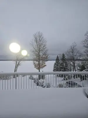 a fence covered in snow next to a lake at Cottage apartments at Lake Huron in Midland